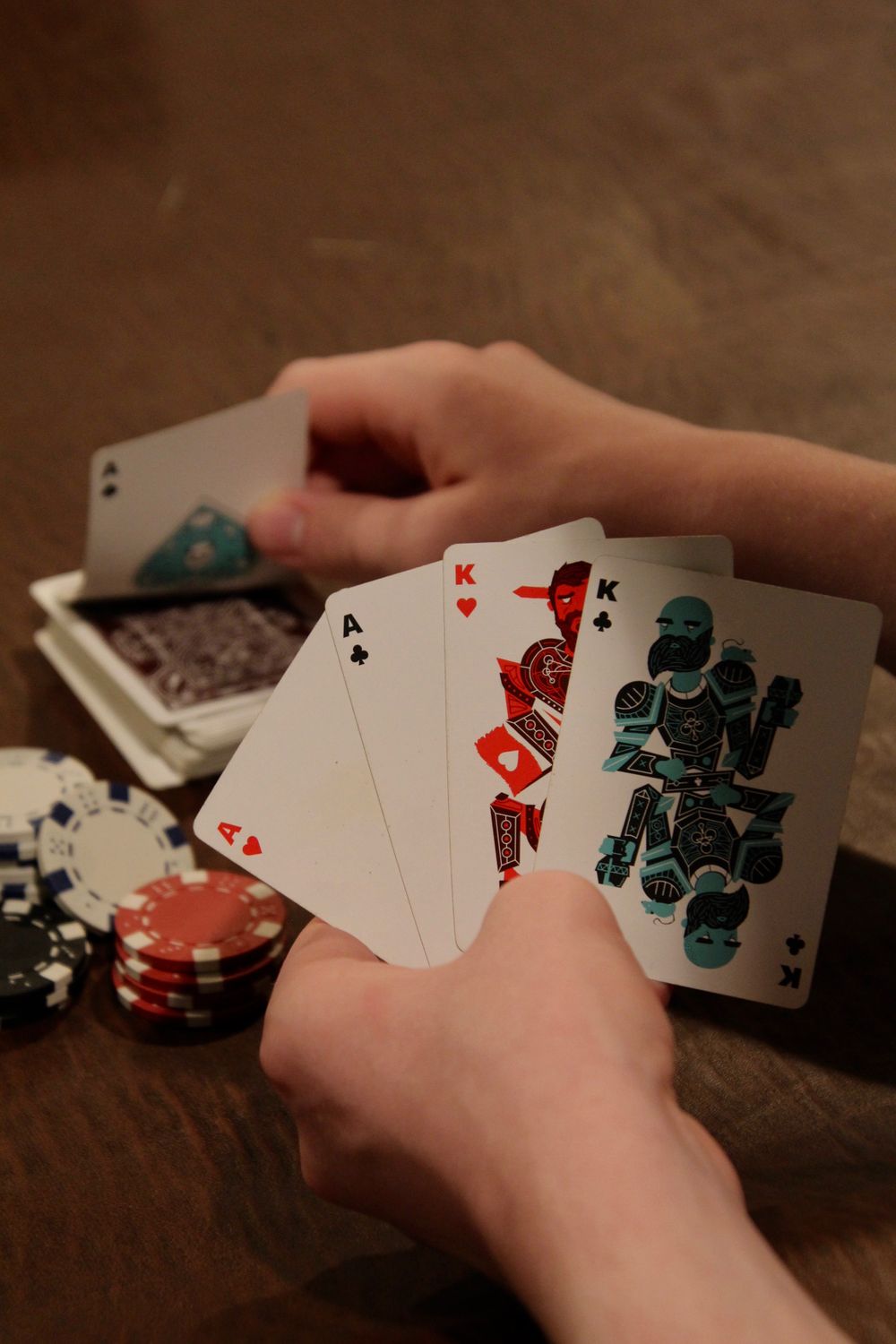 Dua kartu jack tergeletak di atas meja hijau bersanding tumpukan chip poker