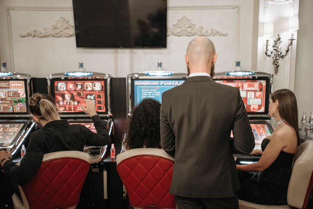 Sekelompok pemain dewasa menikmati mesin slot sambil bersantai di area permainan kasino